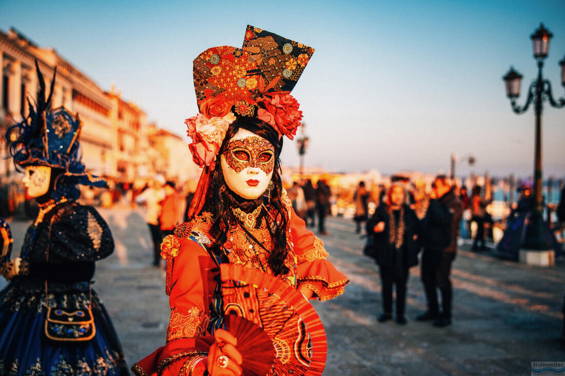 Красивая женщина в красном костюме и традиционной маске во время Венецианского карнавала, 2023 год.